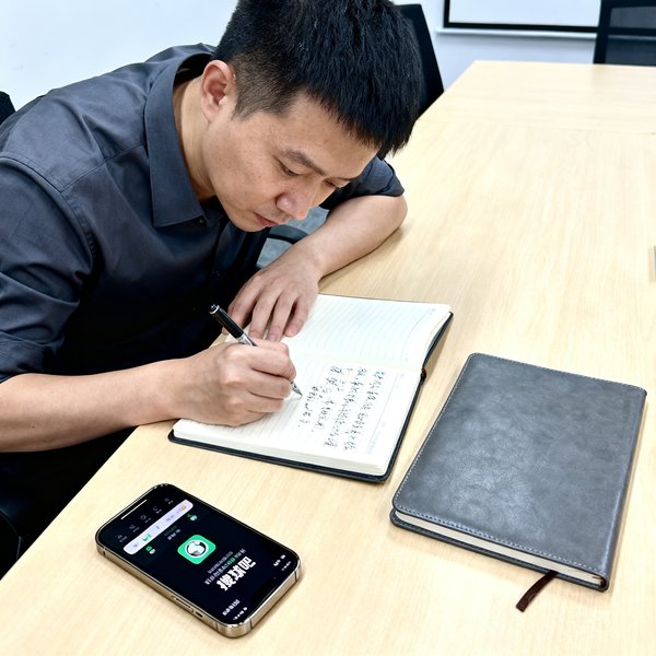 产品总监赵凯在用户访谈会上认真记录反馈，桌面上摆放着手机和笔记本，屏幕上显示搜球吧产品界面